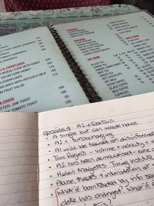 Handwriting in a notebook that is sitting on top of a cafe menu